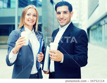 Businesswoman and her partner are standing with folder and coffee Businesswoman and her partner are standing with folder and coffee 34752114