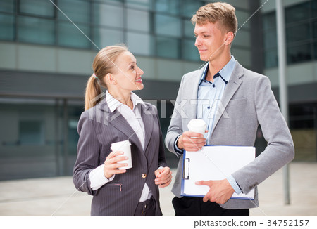 Businesswoman and her partner are standing with folder and coffee 34752157