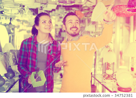 Cheerful man points to stylish model lamp 34752381