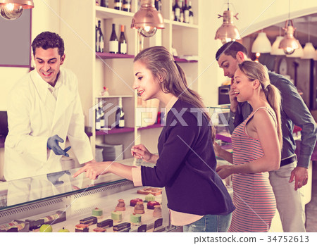 Man with two women are choosing delicious cakes from showcase Man with two women are choosing delicious cakes from showcase 34752613