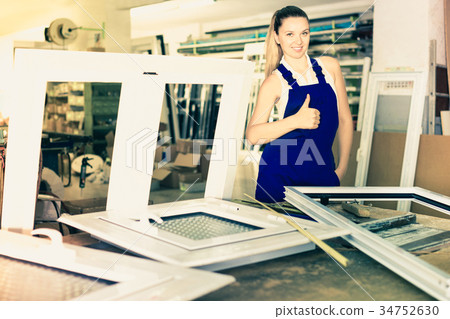 workwoman with plastic window frame in workshop giving thumbs up 34752630