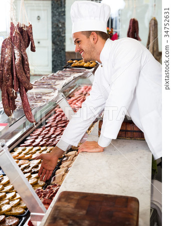 Seller in working clothes taking raw meat 34752631