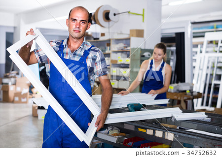 Workman in workwear is standing with window frame from pvc profile 34752632