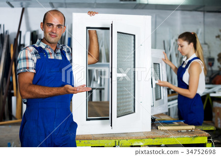 Workman in blue overalls demonstrating pvc window Workman in blue overalls demonstrating pvc window 34752698