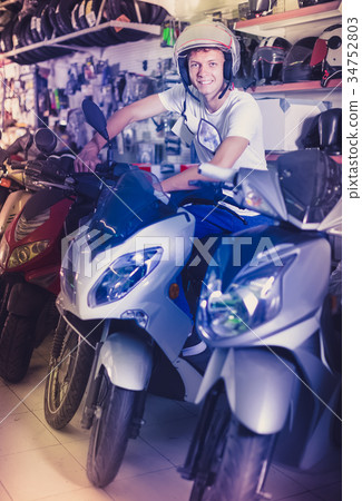 Portrait of glad male in helmet on motorbike in the store 34752803