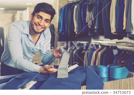Customer man is showing jacket and tie that he chose 34753073