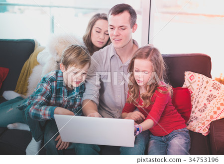 Young cheerful family watching movie on laptop together at home Young cheerful family watching movie on laptop together at home 34753196
