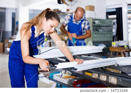Female worker cutting metal-plastic profiles in workshop, using nippers Female worker cutting metal-plastic profiles in workshop, using nippers 34753266