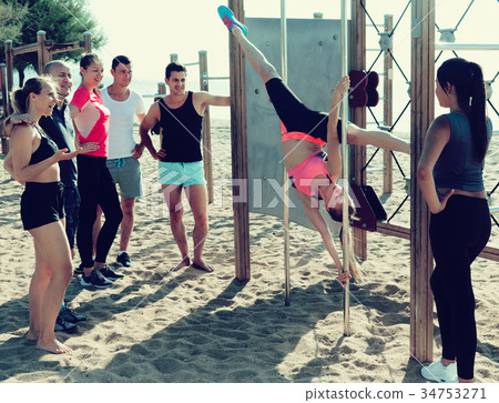 Girl practicing pole exercises on beach Girl practicing pole exercises on beach 34753271
