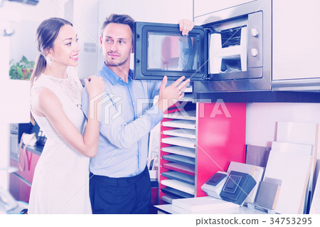 Young husband and wife are choosing new microwave Young husband and wife are choosing new microwave 34753295
