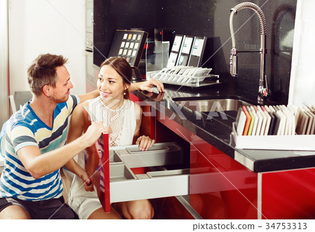 cheerful family couple looking at kitchen tabletop in furniture workshop cheerful family couple looking at kitchen tabletop in furniture workshop 34753313
