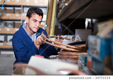 Man assistant is checking rolls of copper trumpet Man assistant is checking rolls of copper trumpet 34753314