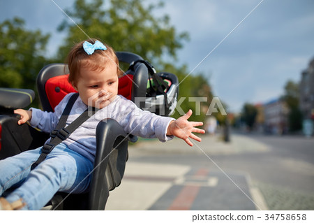 girl sitting in a baby bike seat of a bicycle of girl sitting in a baby bike seat of a bicycle of 34758658
