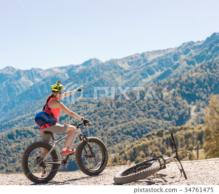Photo of woman in helmet on bicycle showing hand 34761475