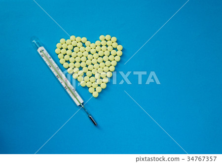 Yellow pills in shape of heart and thermometer 34767357