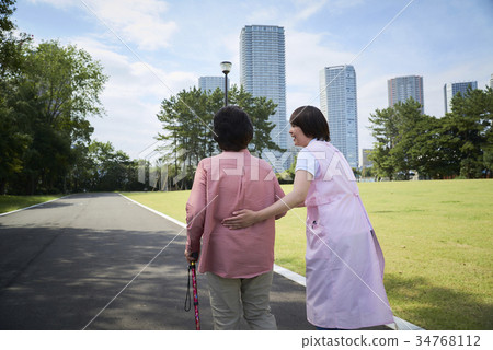 Back view of senior and helper taking a walk with a cane Back view of senior and helper taking a walk with a cane 34768112