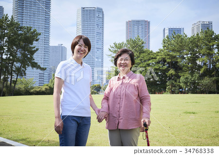 Smiling senior and helper to walk with a cane 34768338