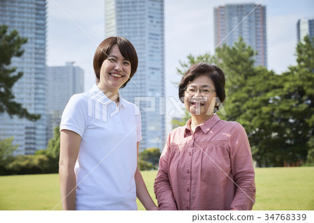 Smiling senior and helper to walk with a cane 34768339