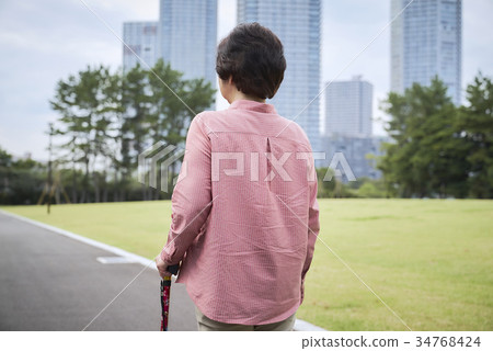 Back view of senior taking a walk with a cane Back view of senior taking a walk with a cane 34768424