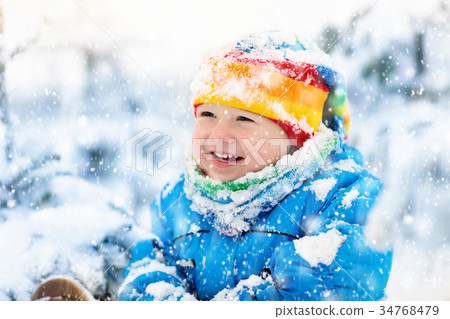 Baby playing with snow in winter. Child in park. 34768479
