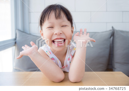 Little girl laughing while sitting in living room Little girl laughing while sitting in living room 34768725