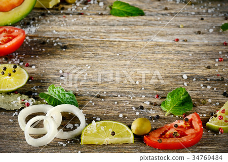 Varied cut vegetables and spices on wooden table.  Varied cut vegetables and spices on wooden table.  34769484