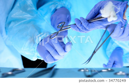 Surgeons hands holding surgical scissors and 34770249