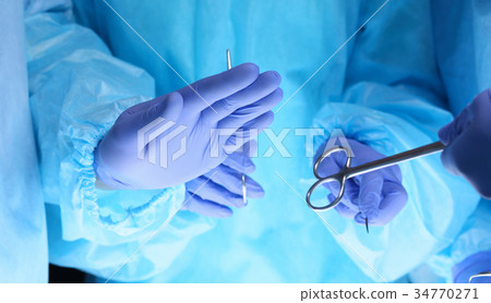 Surgeons hands holding surgical scissors and 34770271