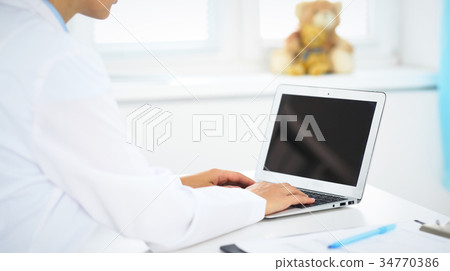 Woman doctor using laptop computer while standing Woman doctor using laptop computer while standing 34770386