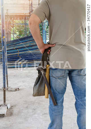 Worker holding tool bag in construction site Worker holding tool bag in construction site 34770417