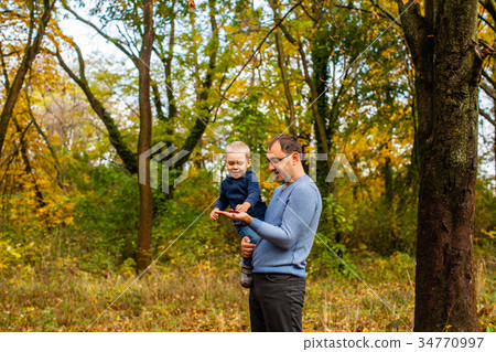 Dad and son in the autumn park 34770997