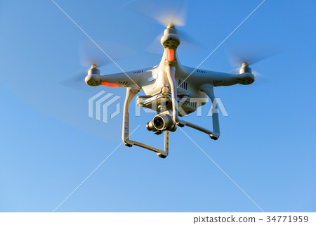 Drone quad copter with camera flying in blue sky 34771959