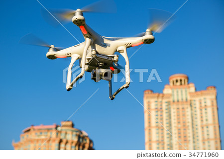 Drone quad copter with camera flying over the city 34771960