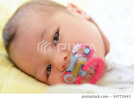 A beautiful newborn girl lies on her bed 34772641