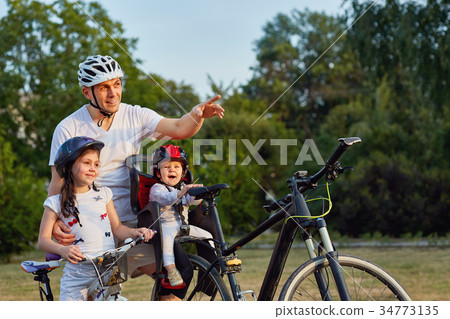 Family in park riding bicycles. Two girls ride Family in park riding bicycles. Two girls ride 34773135