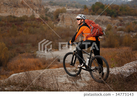 back view of a man with a bicycle and red backpack 34773143