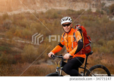 back view of a man with a bicycle and red backpack 34773147