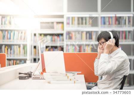 Young Asian man listening to music in library 34773603