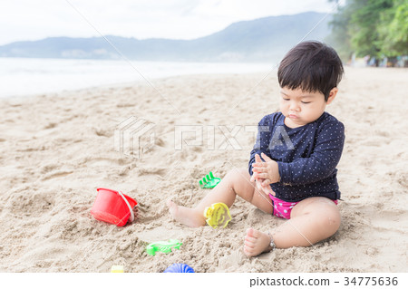 Adorable girl learning and playing on the beach. 34775636