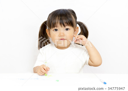 Looking at camera of little girl playing drawing with crayon 34775947