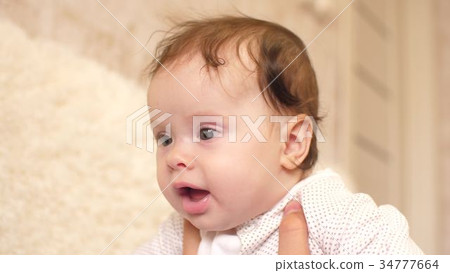 Baby is held in his arms and he laughs. 34777664