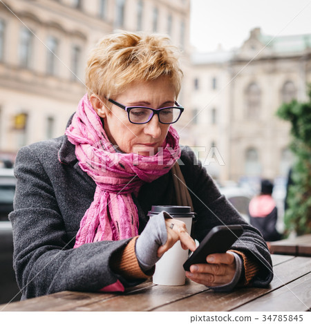 Woman browsing smartphone in outside cafe 34785845