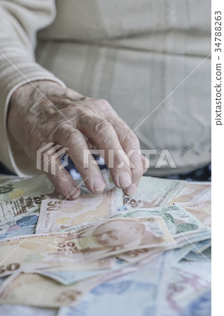 Closeup of wrinkled hand on turkish lira banknotes Closeup of wrinkled hand on turkish lira banknotes 34788263