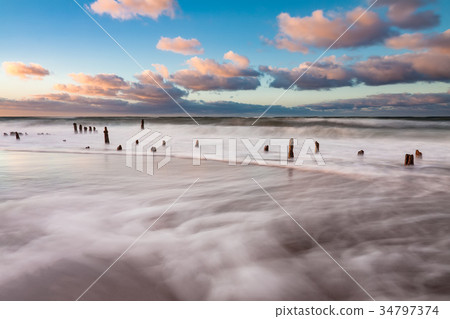 Groynes on shore of the Baltic Sea on a stormy day Groynes on shore of the Baltic Sea on a stormy day 34797374