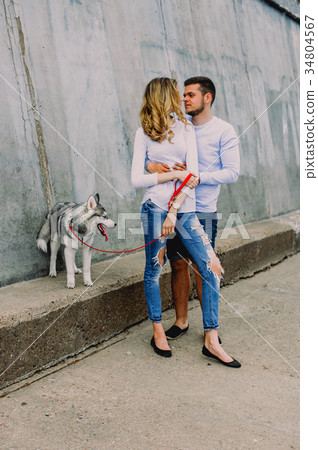 Beautiful young couple playing with a dog husky  34804567