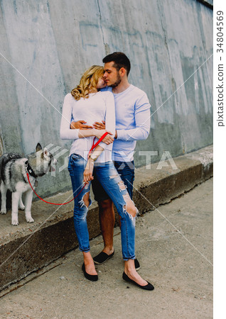 Beautiful young couple playing with a dog husky Beautiful young couple playing with a dog husky 34804569