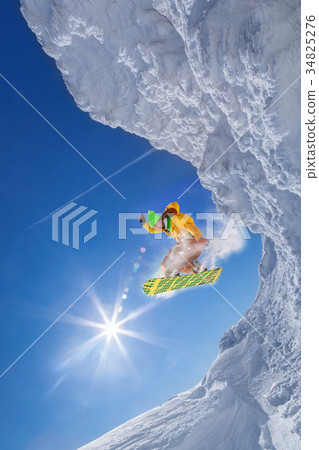 Snowboarder jumping against blue sky 34825276