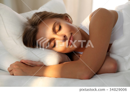 Beautiful young woman sleeping while lying in bed 34829006