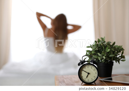 Alarm clock standing on bedside table has already 34829120