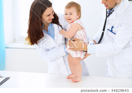 Happy cute baby at health exam at doctor's offic Happy cute baby at health exam at doctor's offic 34829643